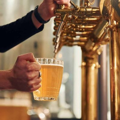 Side view of man's hands that fills glasses by beer